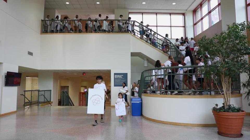 Camp participants descending a staircase with Camp Dream Speak Live signs
