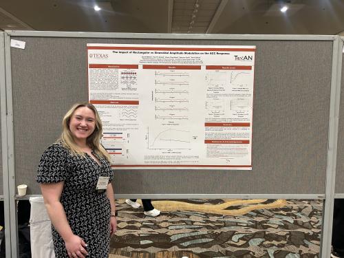 Sarah Medina in a black and white dress presenting research on a poster